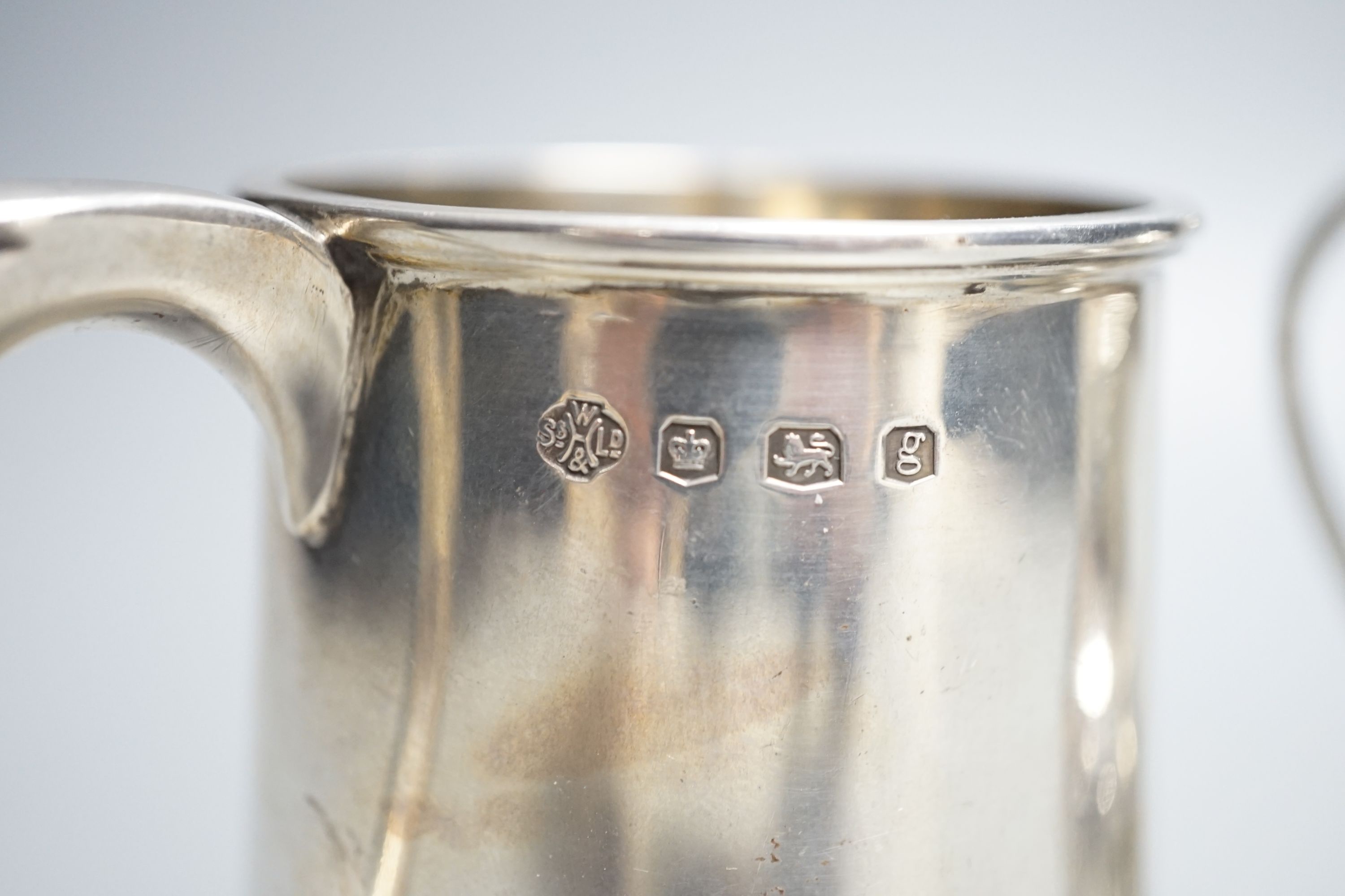 A late Victorian silver cream jug, Nathan & Hayes, Chester, 1897 and a George V silver christening mug, William Hutton & Sons, Sheffield, 1924